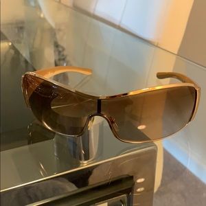 Tan Prada glasses with gold rims.